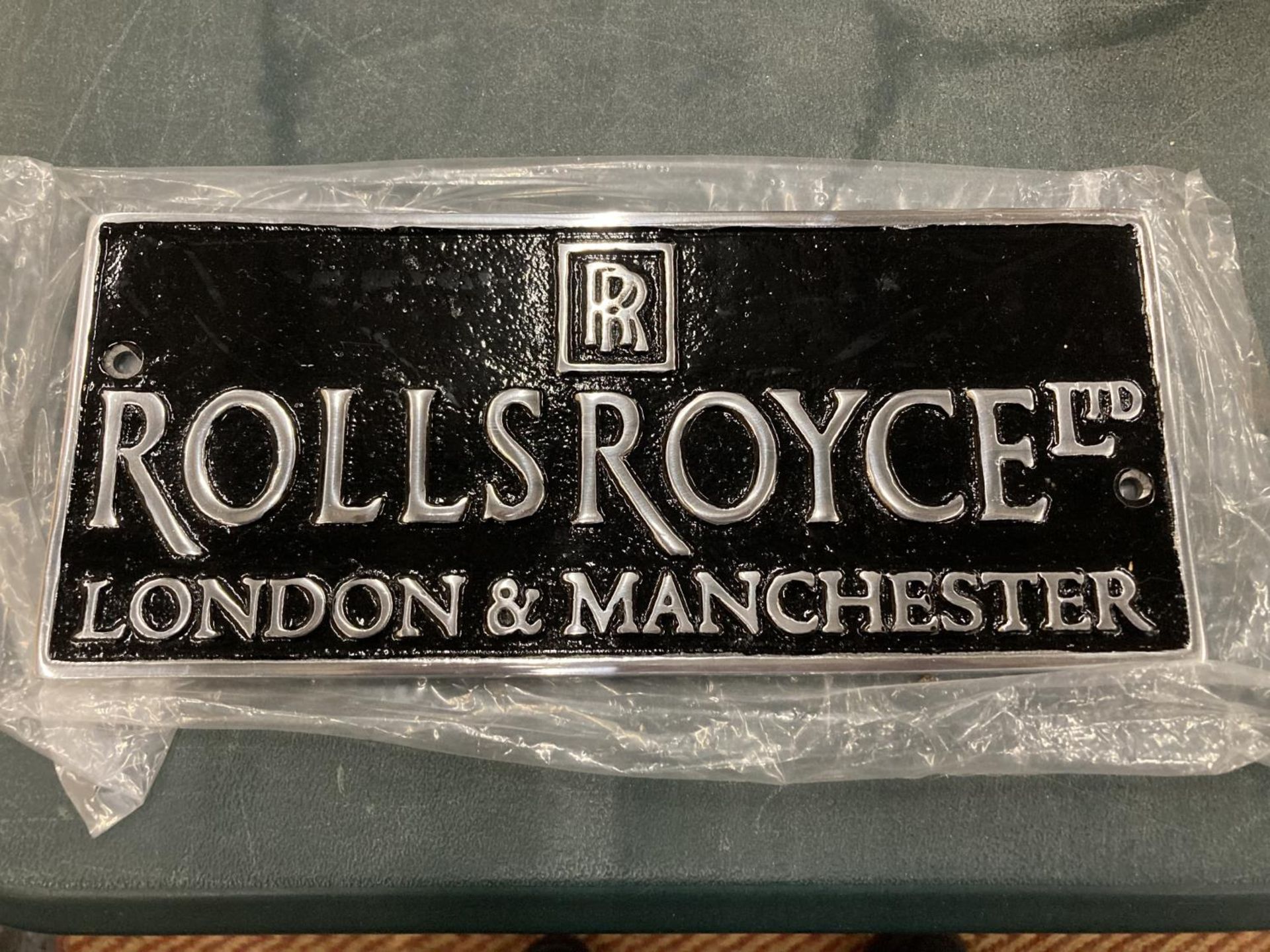 A BLACK AND CHROME ROLLS ROYCE SIGN 24.5CM X 10CM