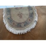 A CREAM PATTERNED OVAL FRINGED RUG