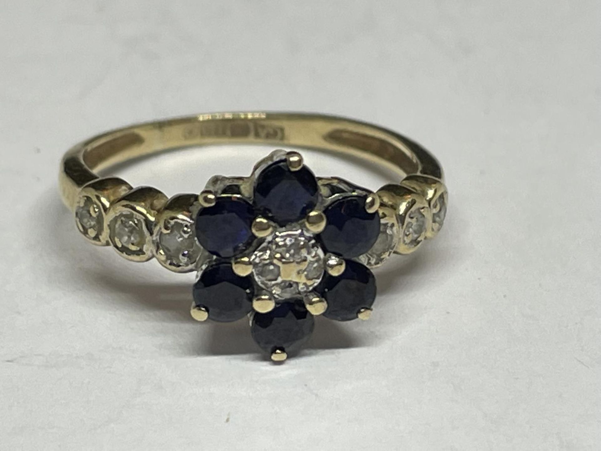 A 9 CARAT GOLD RING WITH SAPPHIRES AND DIAMONDS IN A FLOWER DESIGN AND DIAMONDS ON THE SHOULDERS