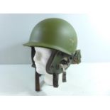 A GREEN PAINTED METAL HELMET AND LINER WITH EAR PIECES