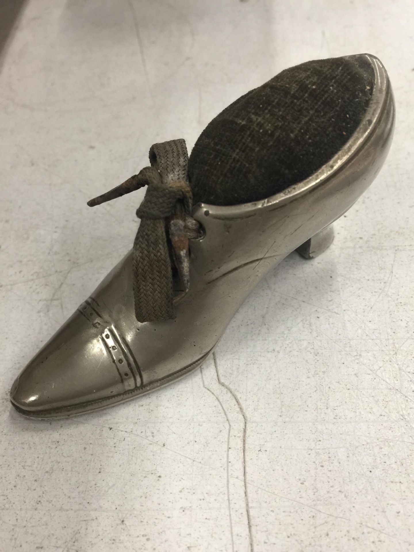 A WHITE METAL SHOE SHAPED PIN CUSHION