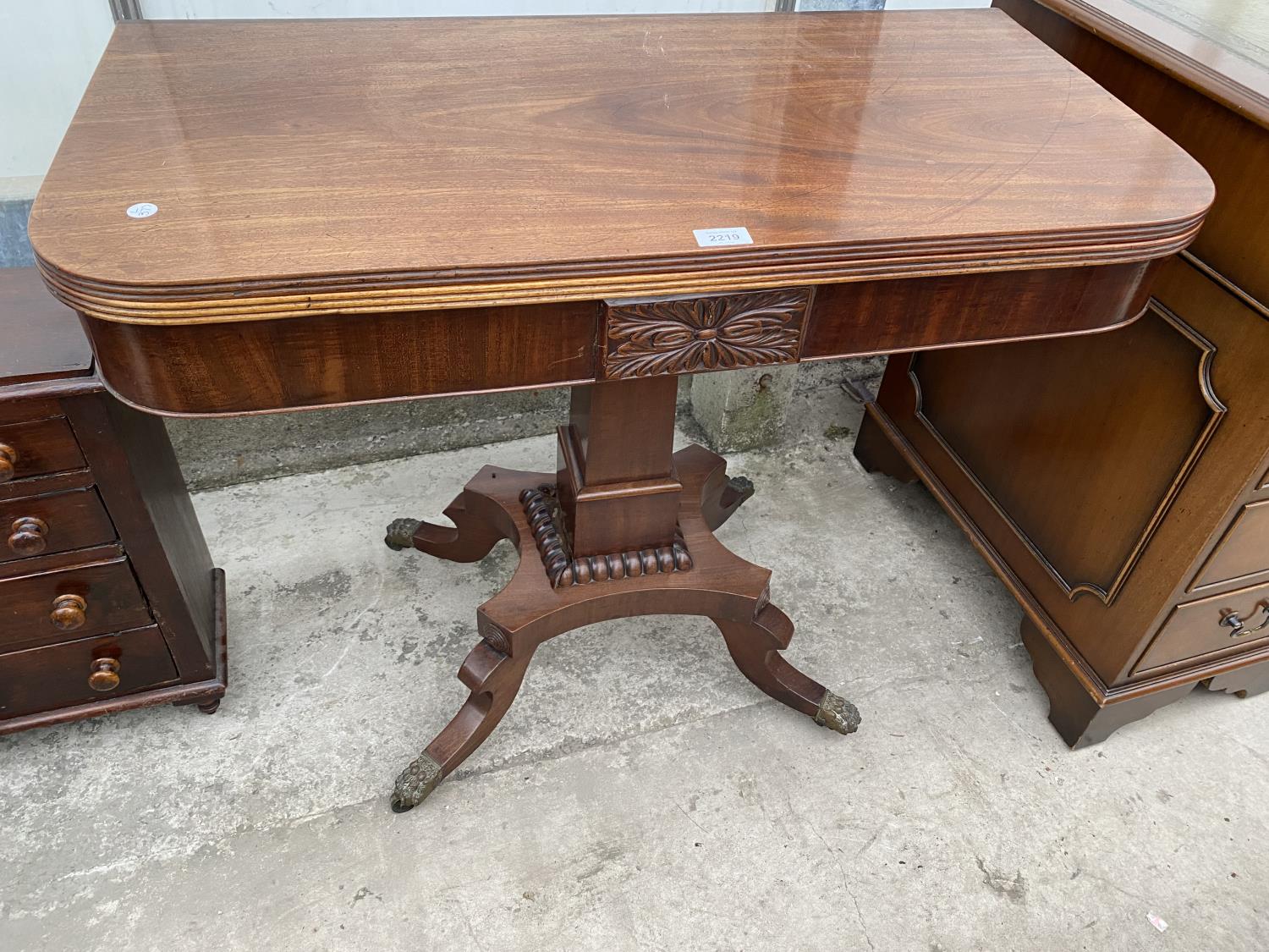 A 19TH CENTURY MAHOGANY FOLD-OVER CARD TABLE ON QUATREFOIL BASE WITH BRASS LION PAW FEET, 35" WIDE