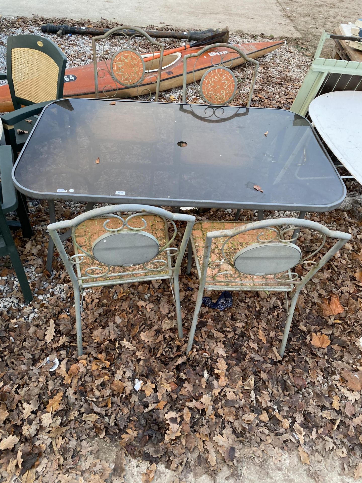 A GLASS TOPPED METAL GARDEN TABLE AND FOUR CHAIRS