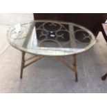 AN OVAL GLASS COFFEE TABLE ON BAMBOO AND WICKER FRAME