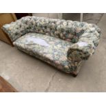 A LATE VICTORIAN CHESTERFIELD SPRUNG AND UPHOLSTERED THREE SEATER SETTEE ON TURNED FRONT LEGS