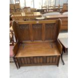 AN OAK JACOBEAN STYLE SETTLE WITH CARVED GOTHIC BACK PANELS, LINENFOLD FRONT PANELS AND LIFT-UP