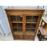 AN OAK 'OLD CHARM' STYLE TWO DOOR GLAZED CABINET WITH LINENFOLD DOORS TO THE BASE, 38" WIDE