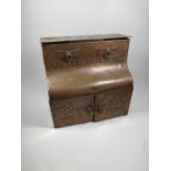 AN ARTS AND CRAFTS 1912 COPPER DESKSTAND WITH LIFT UP TOP SECTION, TWO SMALL DRAWERS AND LOWER DOORS