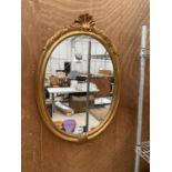 AN OVAL GILT FRAMED WALL MIRROR