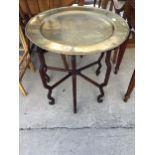 A CHINESE HARDWOOD FOLDING TABLE, 26" DIA WITH DISHED BRASS TOP