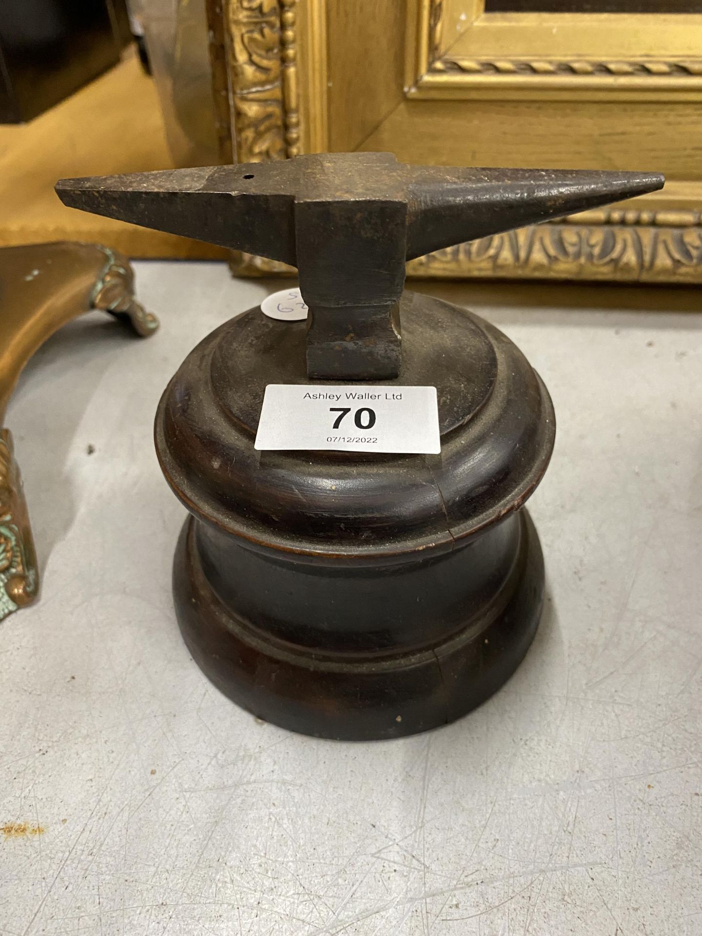 A METAL MINIATURE ANVIL ON WOODEN BASE