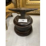 A METAL MINIATURE ANVIL ON WOODEN BASE