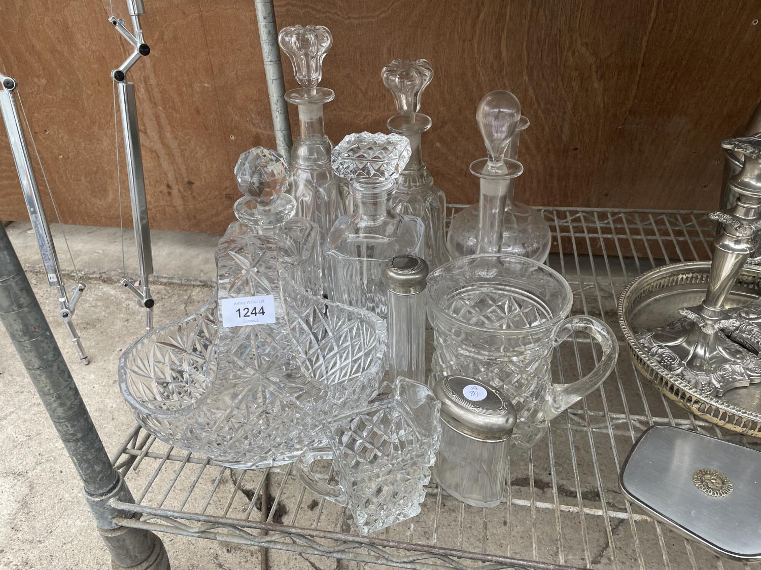 AN ASSORTMENT OF GLASS ITEMS TO INCLUDE DECANTORS, JUGS AND A BASKET ETC