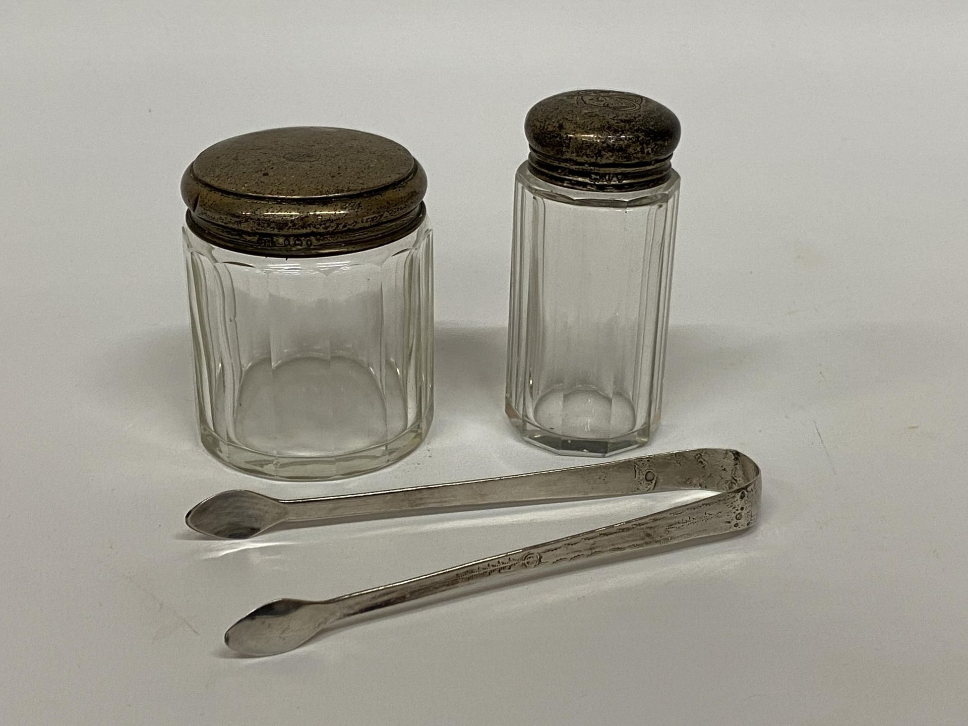 TWO HALLMARKED SILVER TOPPED DRESSING TABLE JARS & FURTHER UNMARKED SUGAR TONGS (3)