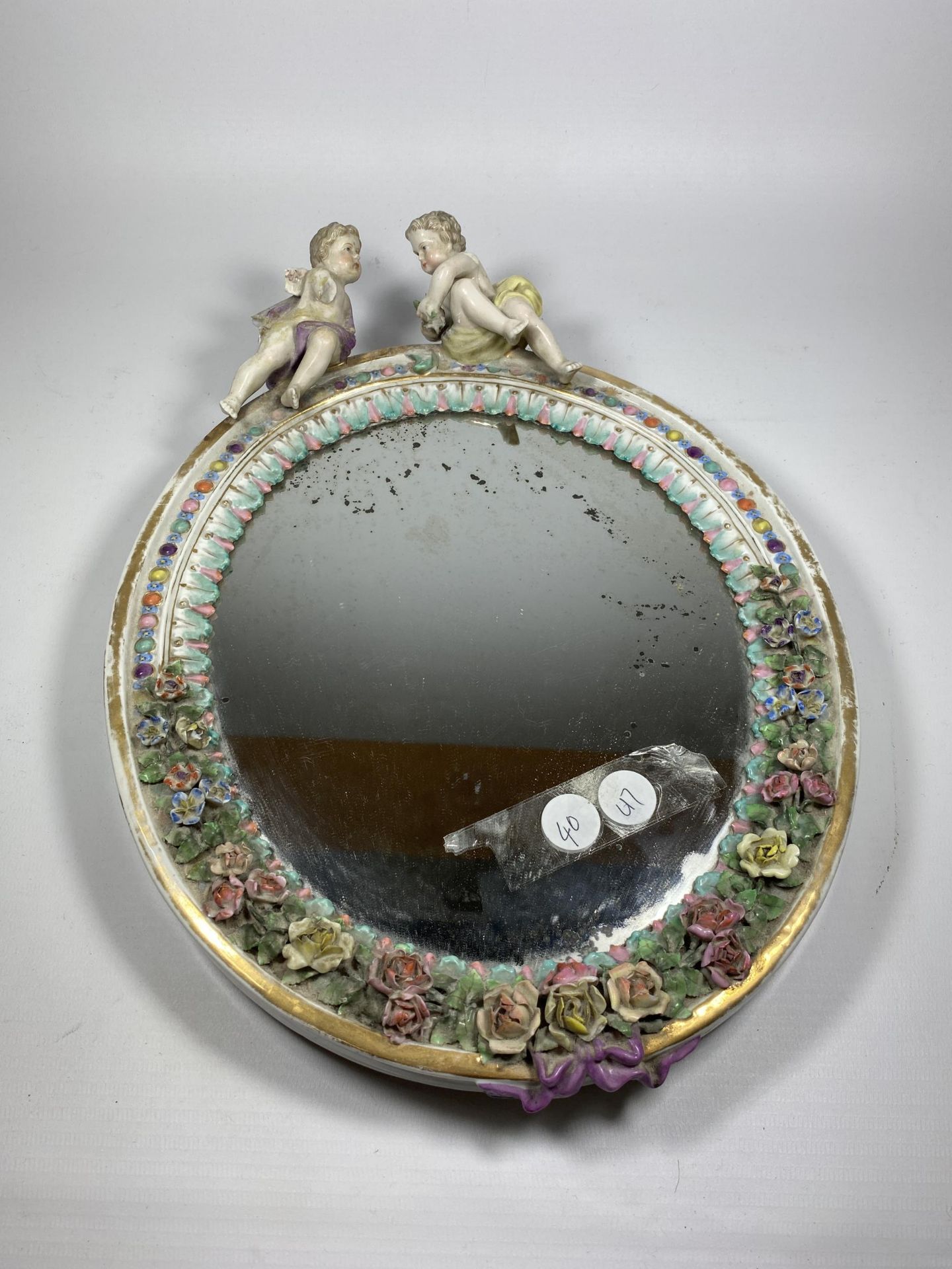 A CONTINENTAL PORCELAIN MIRROR WITH CHERUB AND FLORAL DESIGN