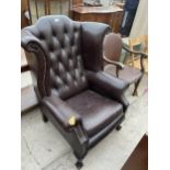 A BROWN FAUX LEATHER WINGED FIRESIDE CHAIR ON FRONT CABRIOLE LEGS, WITH BALL AND CLAW FEET