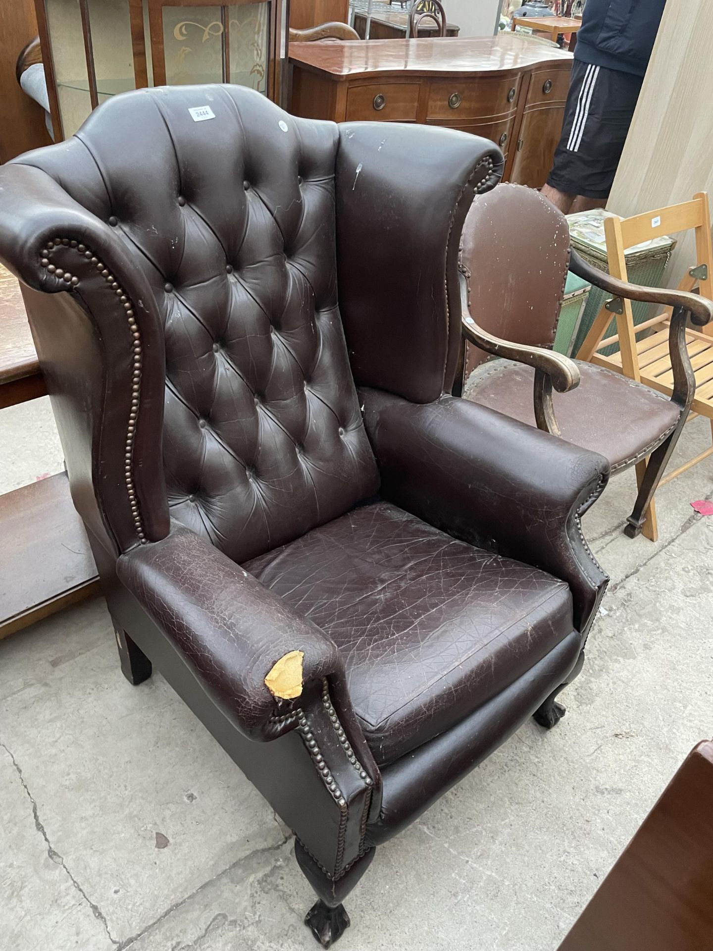 A BROWN FAUX LEATHER WINGED FIRESIDE CHAIR ON FRONT CABRIOLE LEGS, WITH BALL AND CLAW FEET