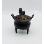 A Japanese bronze lidded incense burner with lion finial on tripod legs