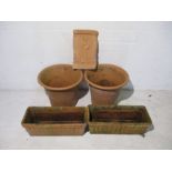 A pair of large terracotta garden pots, along with two matching troughs and a plaque.