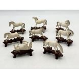 A collection of eight Chinese antique ivory carved horses on hardwood bases - one with hind leg
