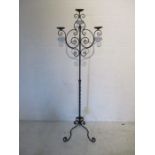 A freestanding wrought iron candelabra on tripod base