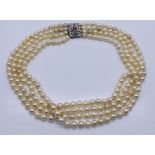 A four strand pearl necklace with an 18ct white gold clasp set with a diamond and rubies