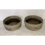 Two round concrete garden planters shaped to look like wooden barrels