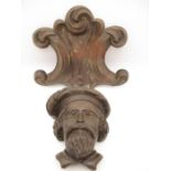 An antique carved wooden head of a Scot wearing a feathered bonnet with feather along with a