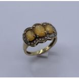 A 9ct gold citrine three stone ring with diamond surround