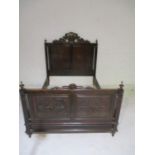 An antique carved oak double bed with coat of arms and Flemish style figures.