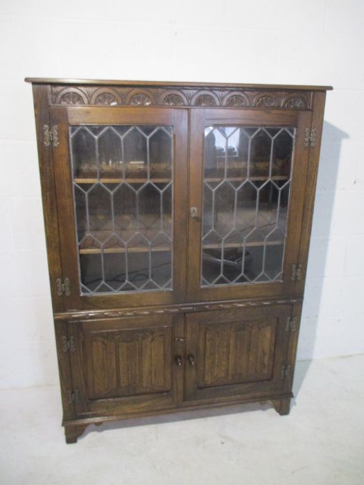 An oak display cabinet with linen fold decoration and cupboard under