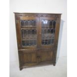 An oak display cabinet with linen fold decoration and cupboard under