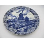 A Delft blue and white charger with traditional Dutch scenes