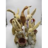 A collection of plant pot holders in the form of Straw Rabbits, plus a wooden duck.