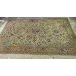 A large green ground rug with red border and floral detail - some fading and damage 376cm x 268cm