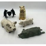 A collection of cast iron and bronze pigs including a pair of bronze pigs holding a pot, a novelty