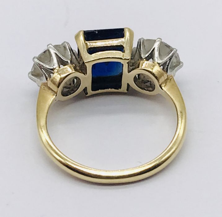 A diamond and sapphire three stone ring. The diamonds measuring 1ct each (6.5mm diameter x 3.75mm - Image 5 of 7