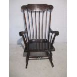 A dark wood stick back rocking chair.