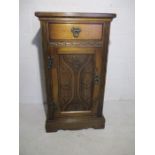 A bedside cabinet with carved decoration to front