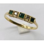 An 18ct gold five stone ring set with emeralds and diamonds