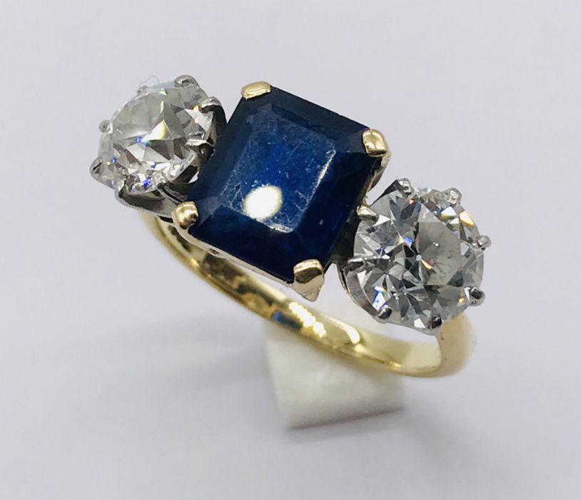 A diamond and sapphire three stone ring. The diamonds measuring 1ct each (6.5mm diameter x 3.75mm - Image 2 of 7