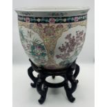 A large Chinese Famille Rose fishbowl on wooden stand - character mark to base