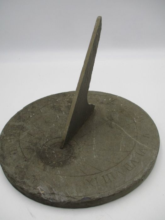 A circular slate sundial with Roman numerals, diameter 24.5cm