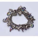 A silver charm bracelet with a quantity of mainly silver charms