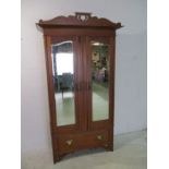 An Art Noveau satin wood two door mirrored wardrobe with single drawer under