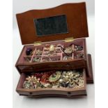 A collection of costume jewellery in wooden box including rings, brooches, earrings, beads etc.
