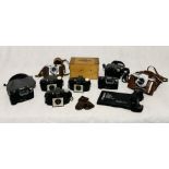 A collection of various cameras and equipment including a Kodak model B developing tank, three