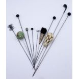 A small collection of vintage hat pins including a hallmarked silver pin in the form of a golf