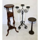 A wrought iron candelabra along with a small carved plant stand and larger example with two drawers