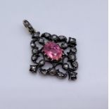 An antique pendant set with old cut diamonds around a central pink stone (possibly tourmaline) set